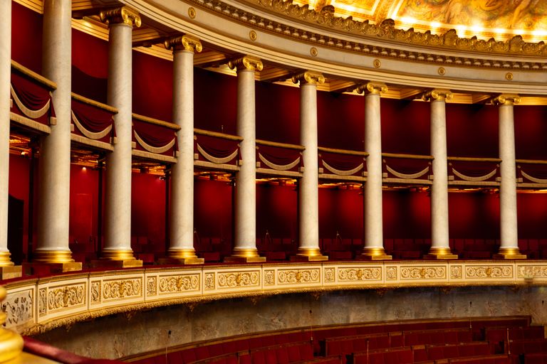 Beautiful ornate interior of an opera house balcony showcasing rich red and gold decor.